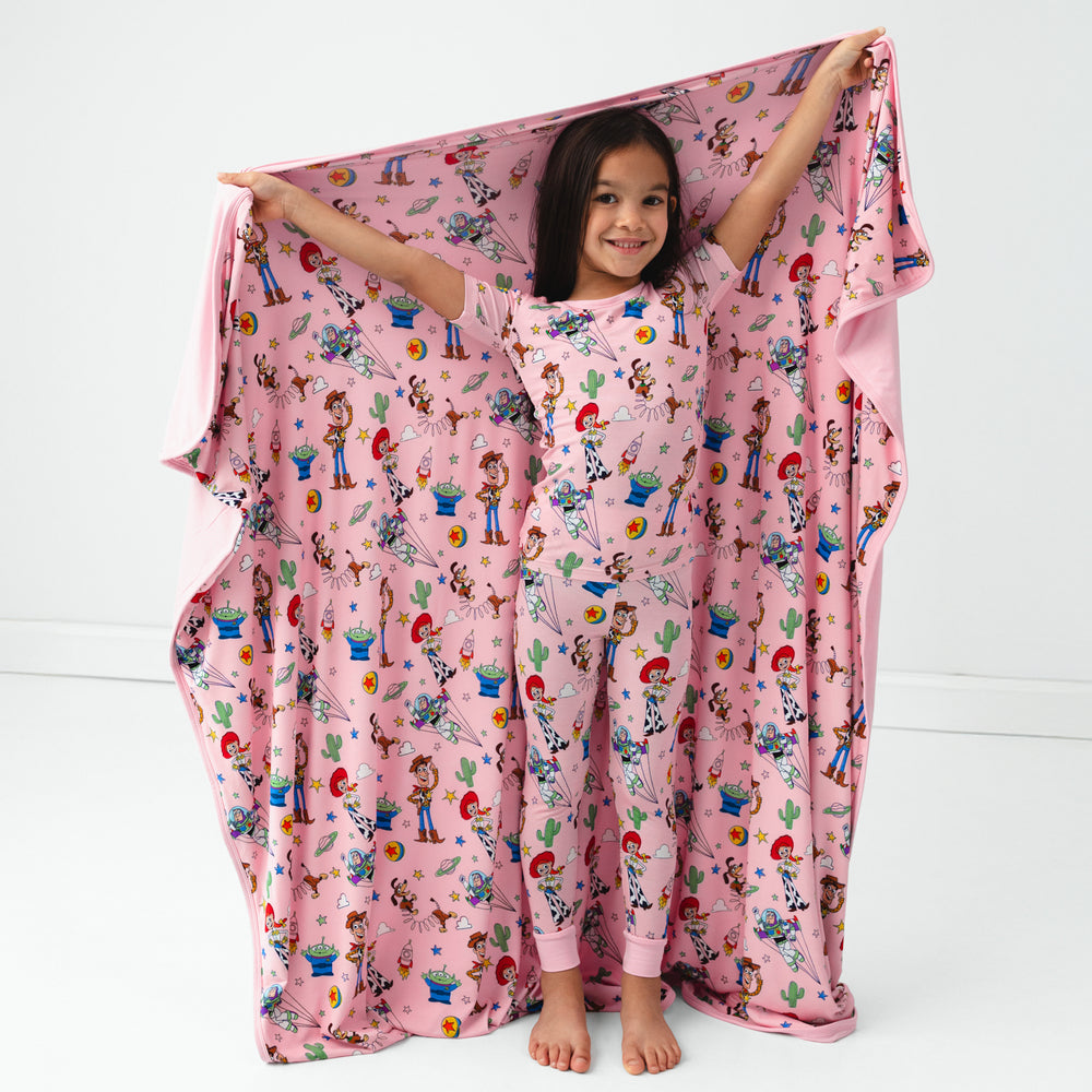 Image of a child holding up a Pink Toy Story Stars cloud blanket