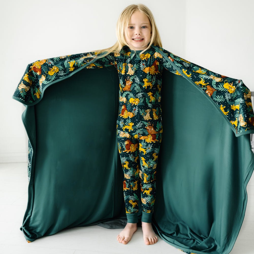 Child wearing Disney Simba's Sky two piece pajama set with a matchign cloud blanket draped over their shoulders