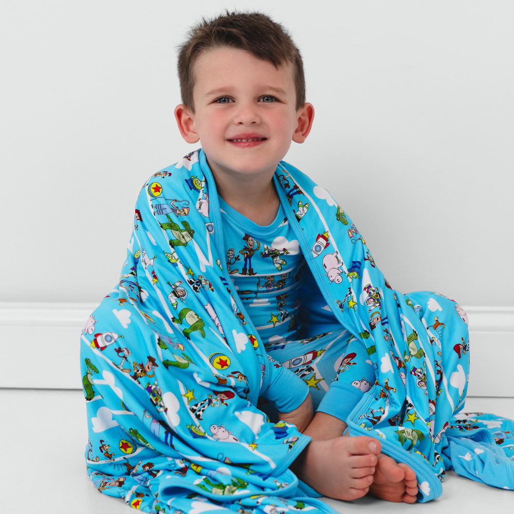 Child sitting on the ground wrapped up in a Disney Pixar Toy Story Pals large cloud blanket