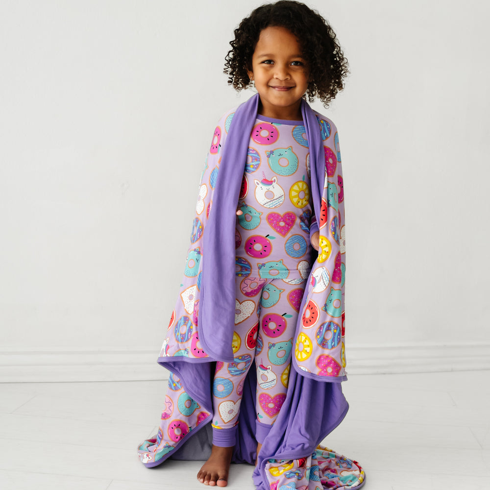 Click to see full screen - Alternate image of a child wearing a Lavender Donut Dreams two piece pajama set with a matching large cloud blanket wrapped around her shoulders