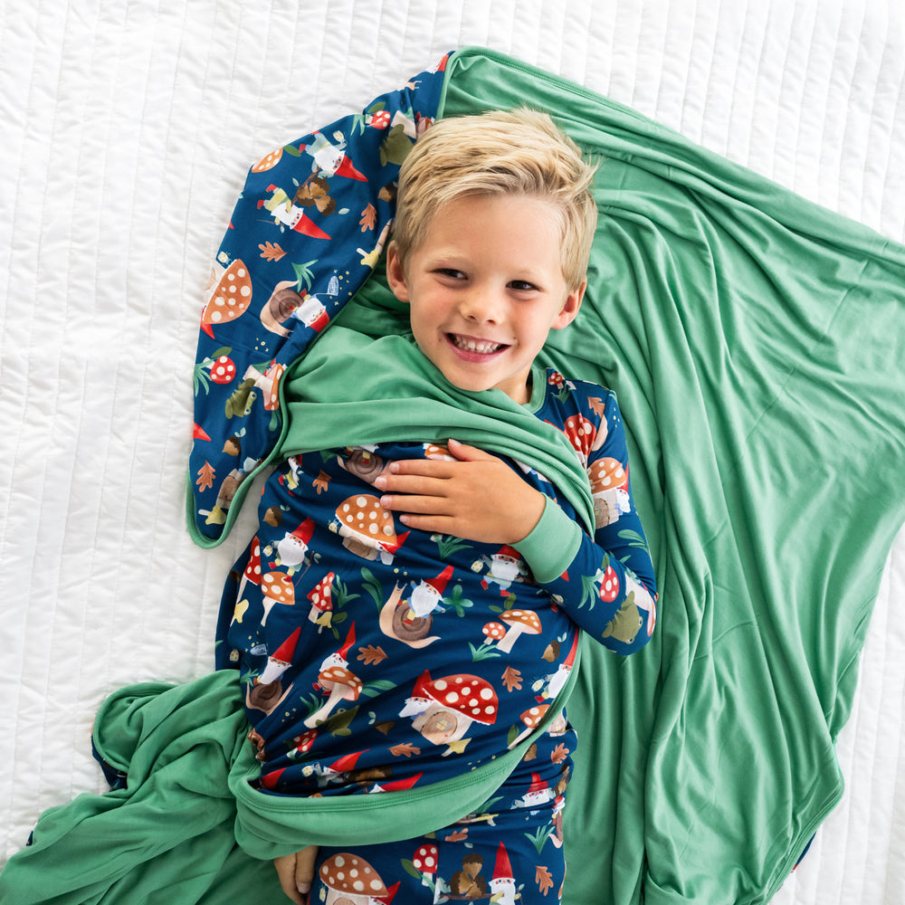 Top view image of the child laying down while wrapped in the Forest Gnomes Large Cloud Blanket®