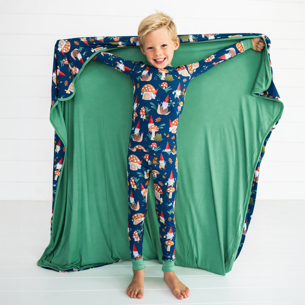 Smiling child posing while displaying the interior of the Forest Gnomes Large Cloud Blanket®