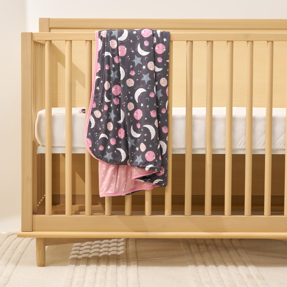 pink to the moon & back blanket laying over crib