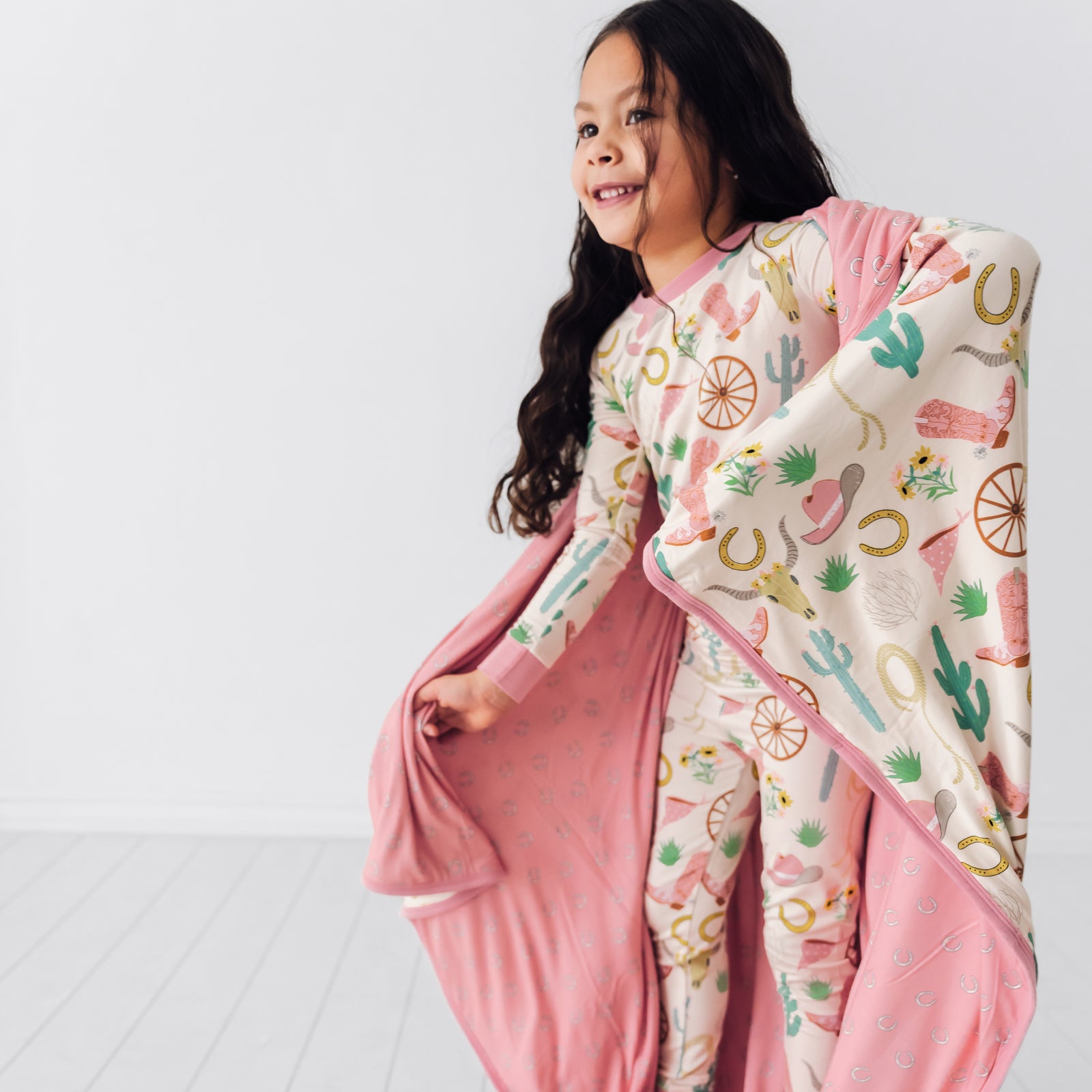 Alternate image of a child wrapped up in a Pink Ready to Rodeo large cloud blanket wearing a matching two piece pajama set