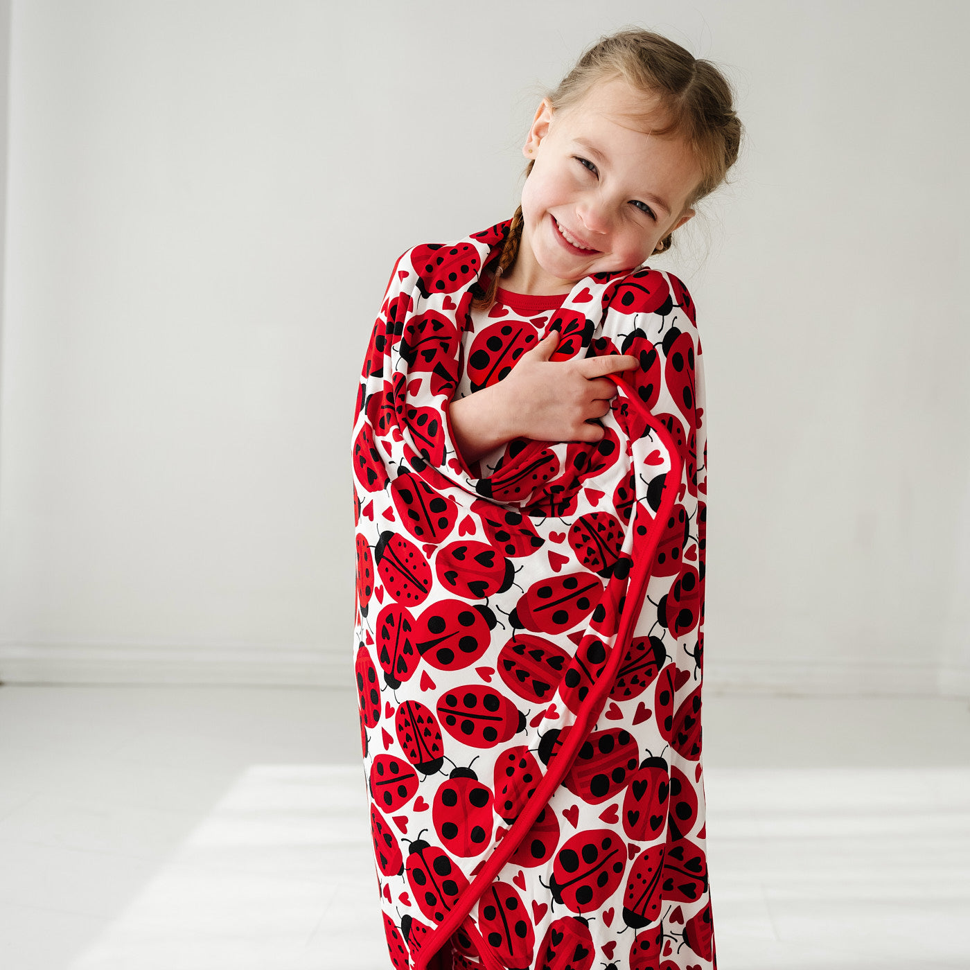 Child wrapped up in a Love Bug printed large cloud blanket