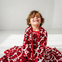 Child sitting on the ground wrapped up in a Love Bug printed large cloud blanket