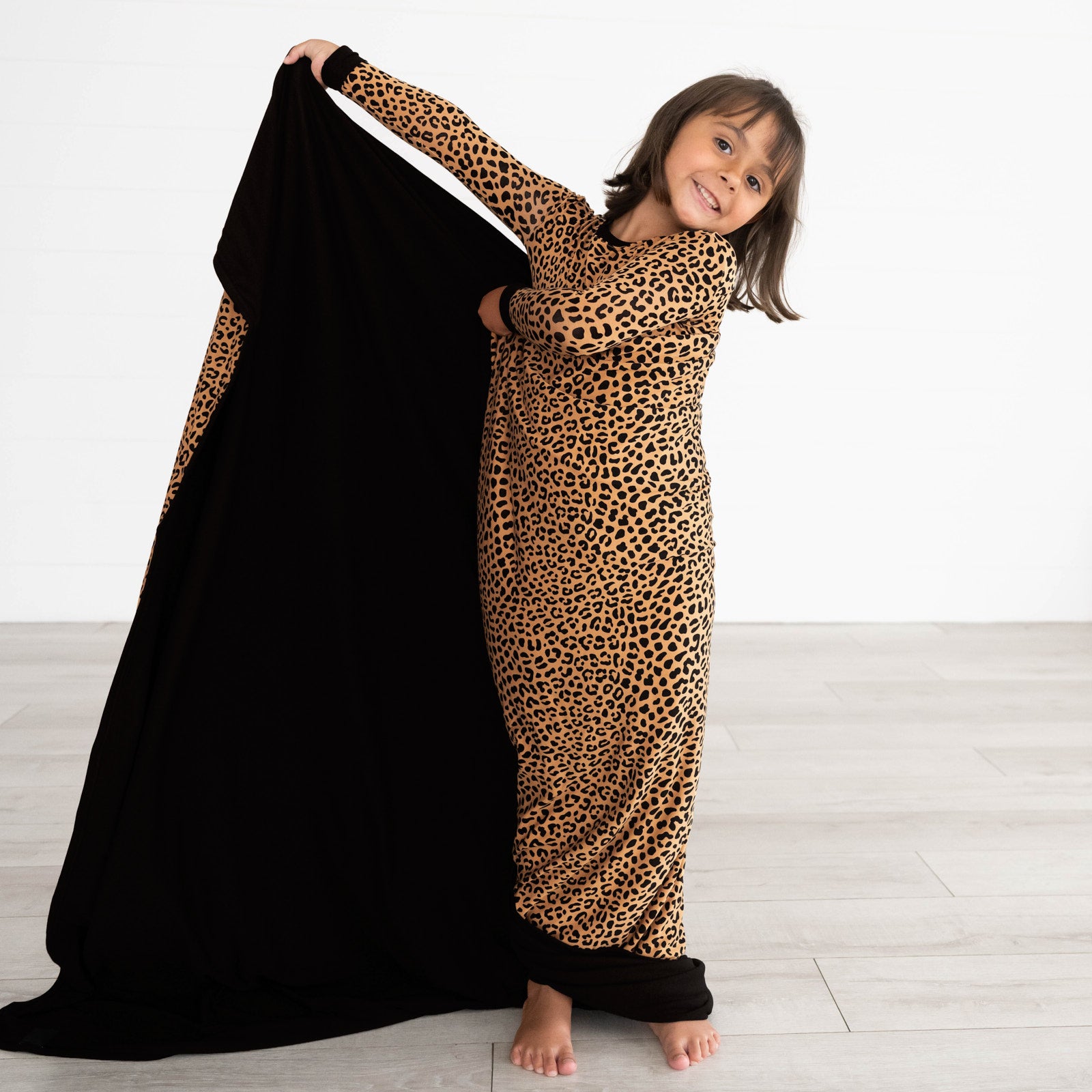 Girl posing with theClassic Leopard Large Cloud Blanket® displaying the inside of the blanket