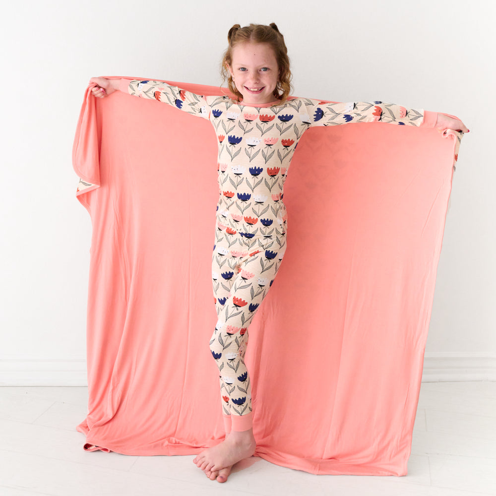 Child holding out a Flower Friends large cloud blanket showing the solid color backing