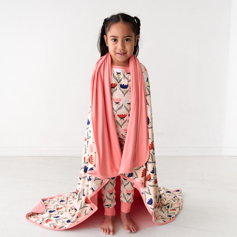Child wrapped up in a Flower Friends large cloud blanket and wearing matching pajamas