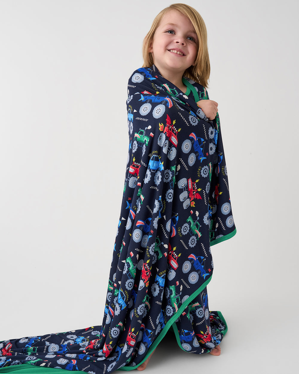 Standing boy wrapped in the Monster Truck Madness Large Cloud Blanket®
