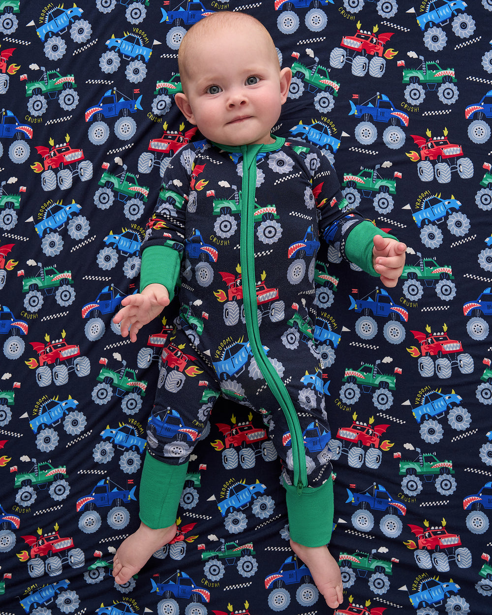 Aerial view of baby wearing the Monster Truck Madness Zippy on a matching cloud blanket