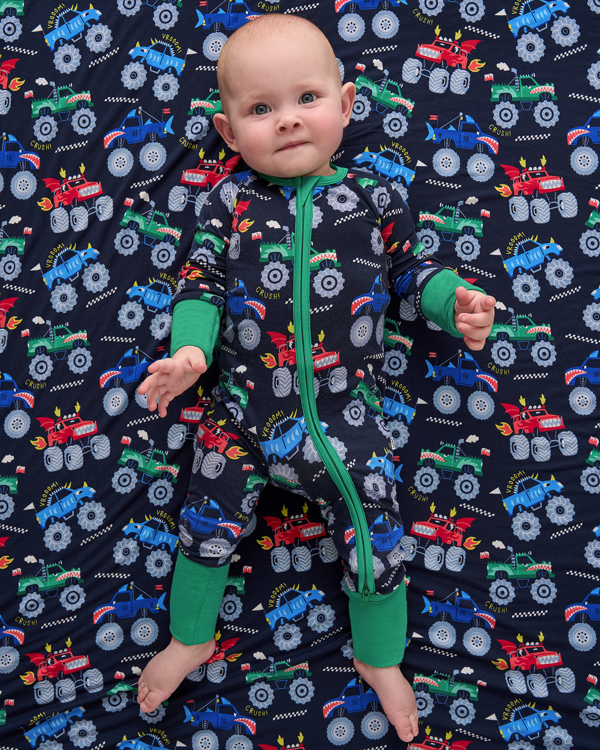 Aerial view of baby wearing the Monster Truck Madness Zippy on a matching cloud blanket