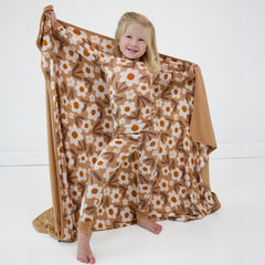 Child posing wearing a Daisy Daydream two piece pj set holding out a matching cloud blanket