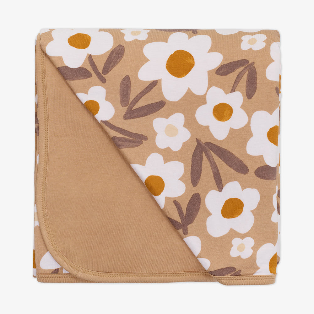 Flat lay image of a Daisy Daydream cloud blanket showing the solid tan backing