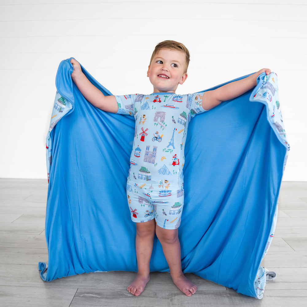 Child posing and showing the inside of the Blue Weekend in Paris Large Cloud Blanket®