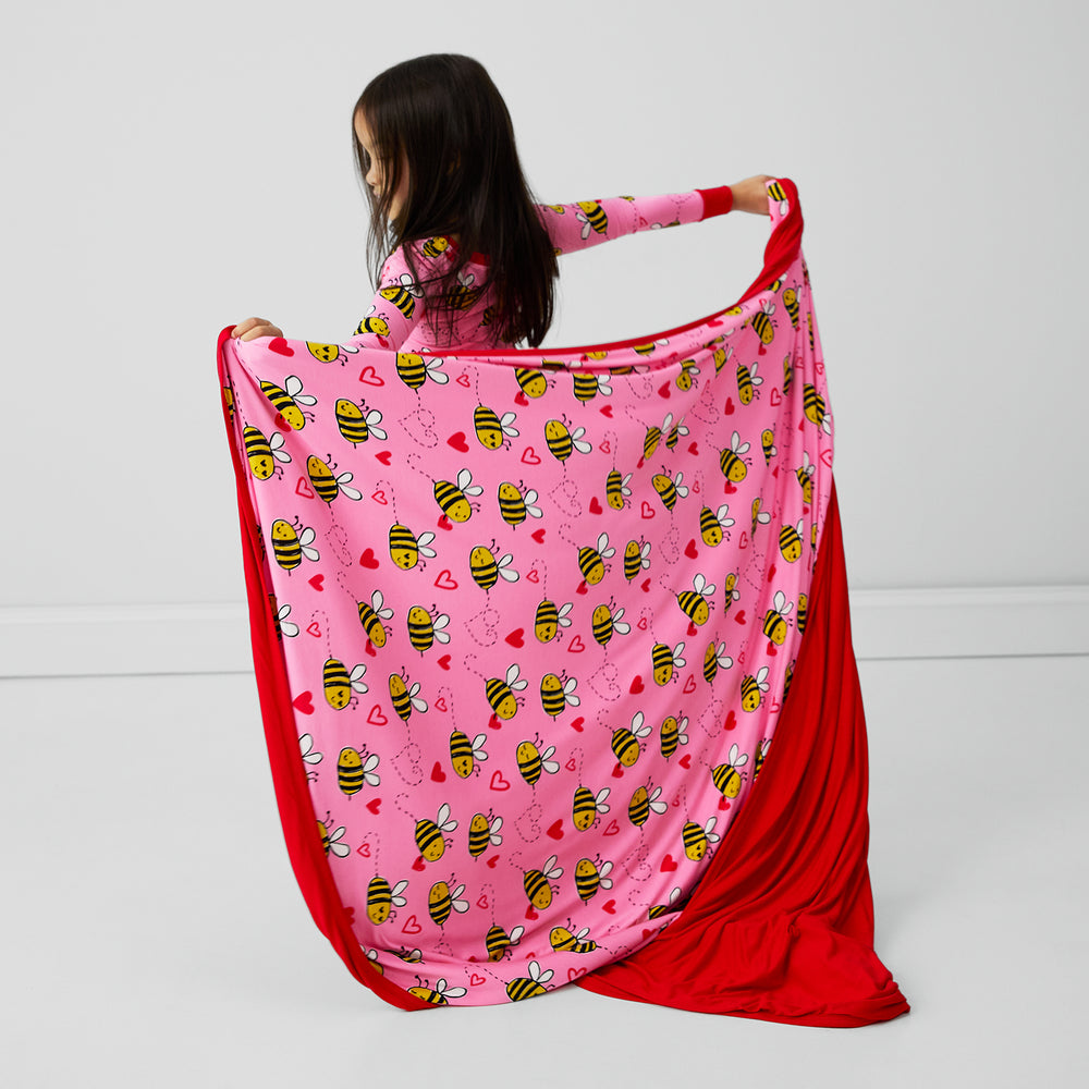 Back view of of a child twirling with a Pink Bee Mine blanket and matching two piece pj set