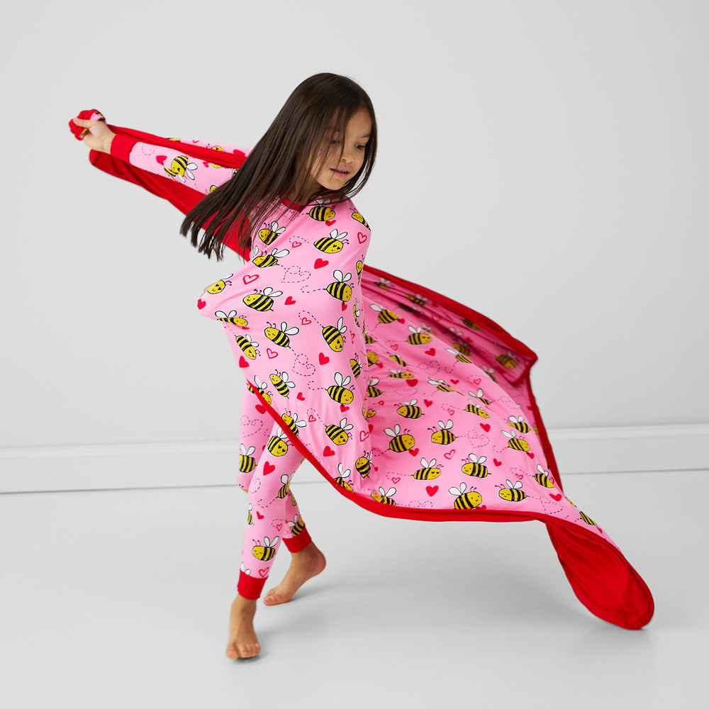 Image of a child twirling with a Pink Bee Mine blanket and matching two piece pj set