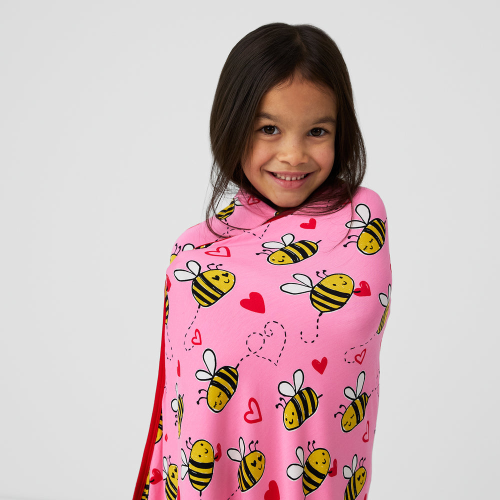 Close up image of a child wrapped up in a Pink Bee Mine cloud blanket