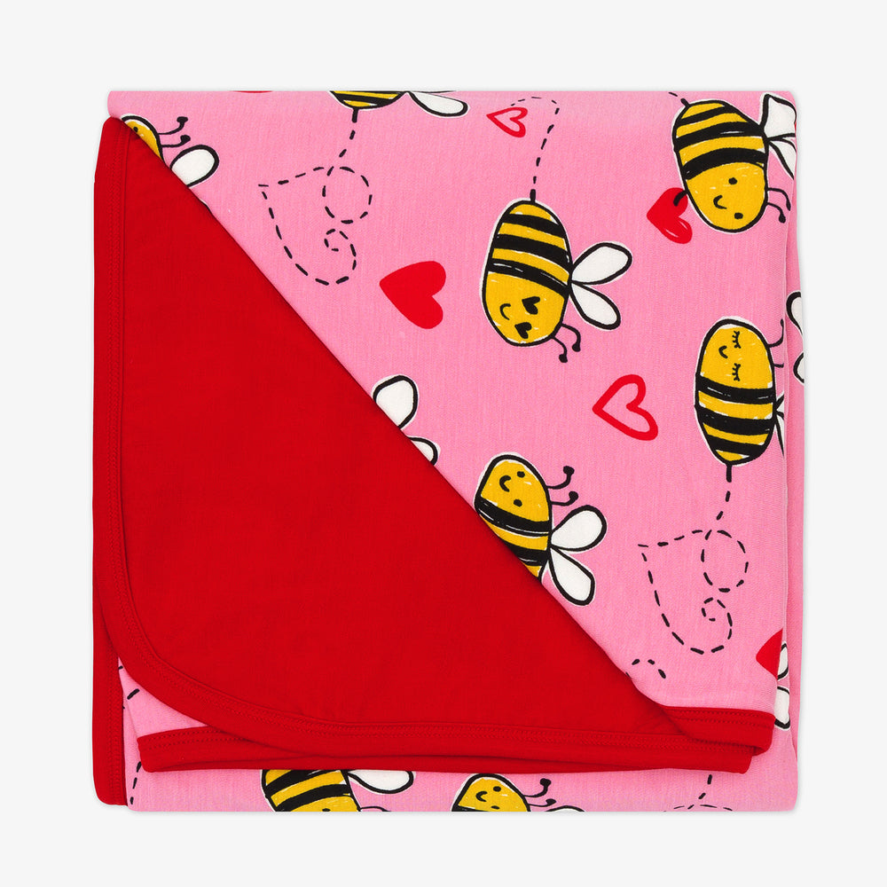 Flat lay image of a Pink Bee Mine Blanket showing the red backing