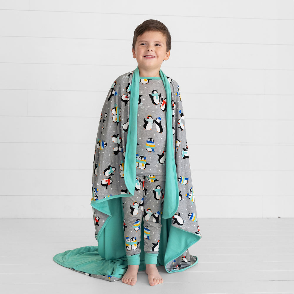 child wearing a Penguin Party blanket over his shoulders and matching two piece pj set