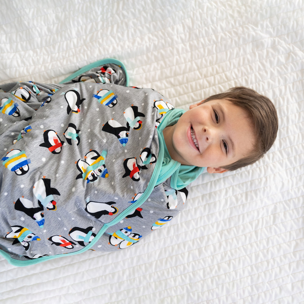 close up image of a child wrapped up in a Penguin Party blanket 