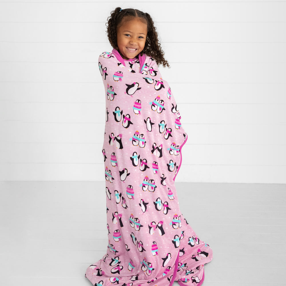 Child wrapped in a Pink Penguin Party blanket