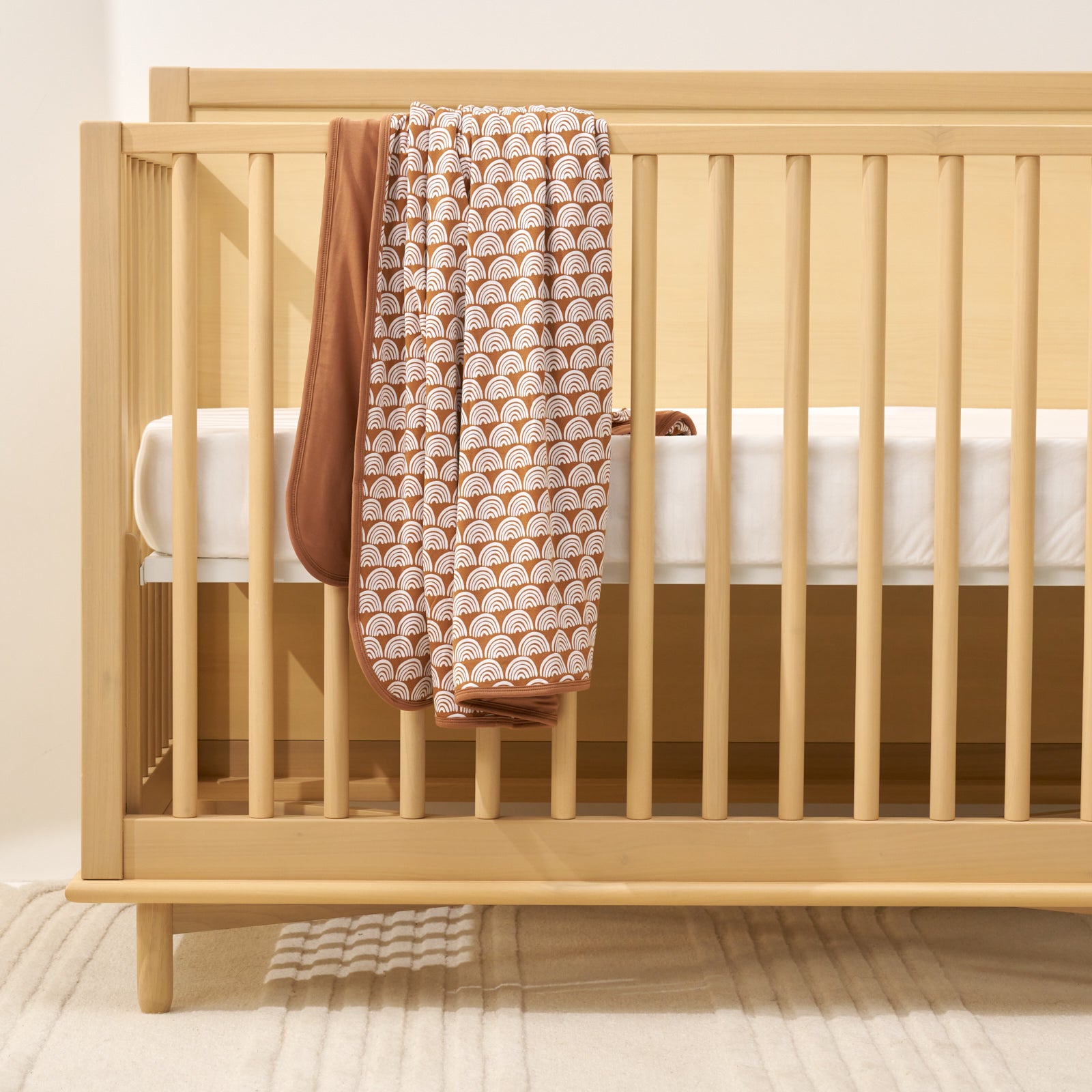rust rainbows blanket laying over crib