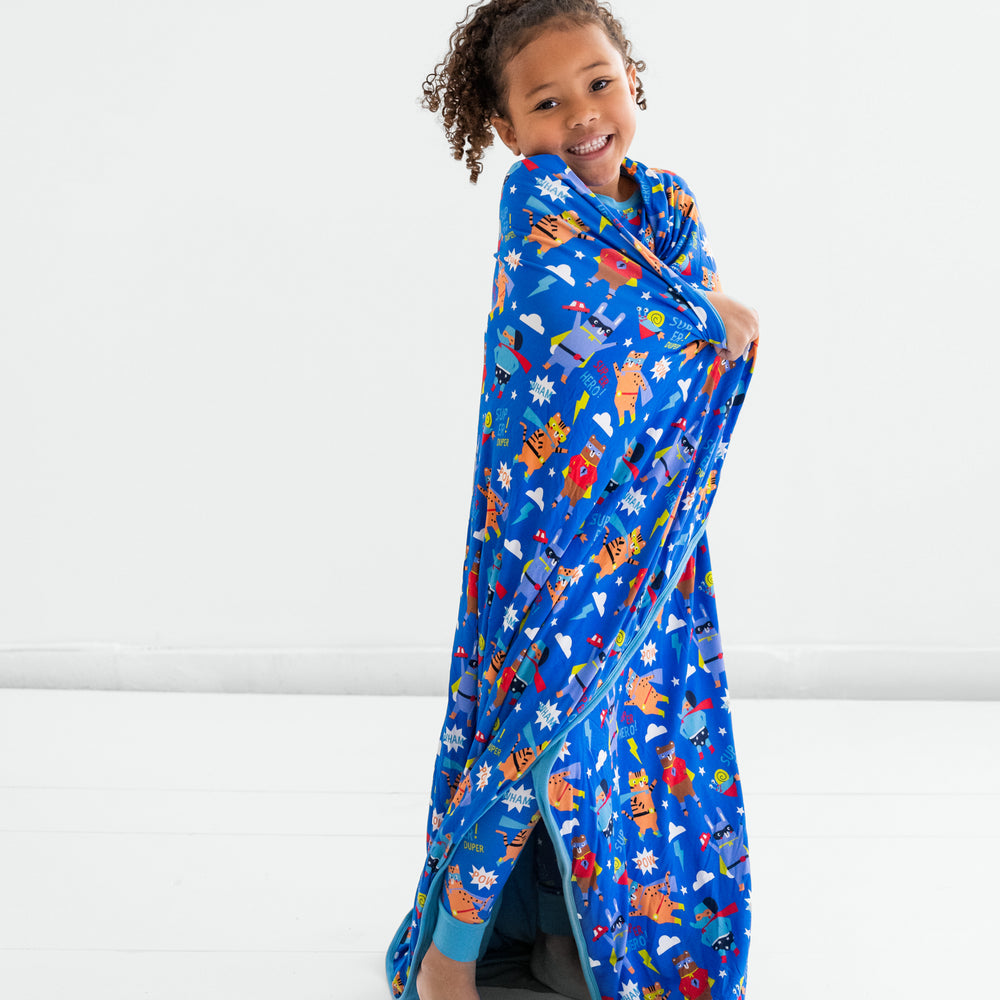 Child standing wrapped in the Blue Sleepy Heroes Cloud Blanket