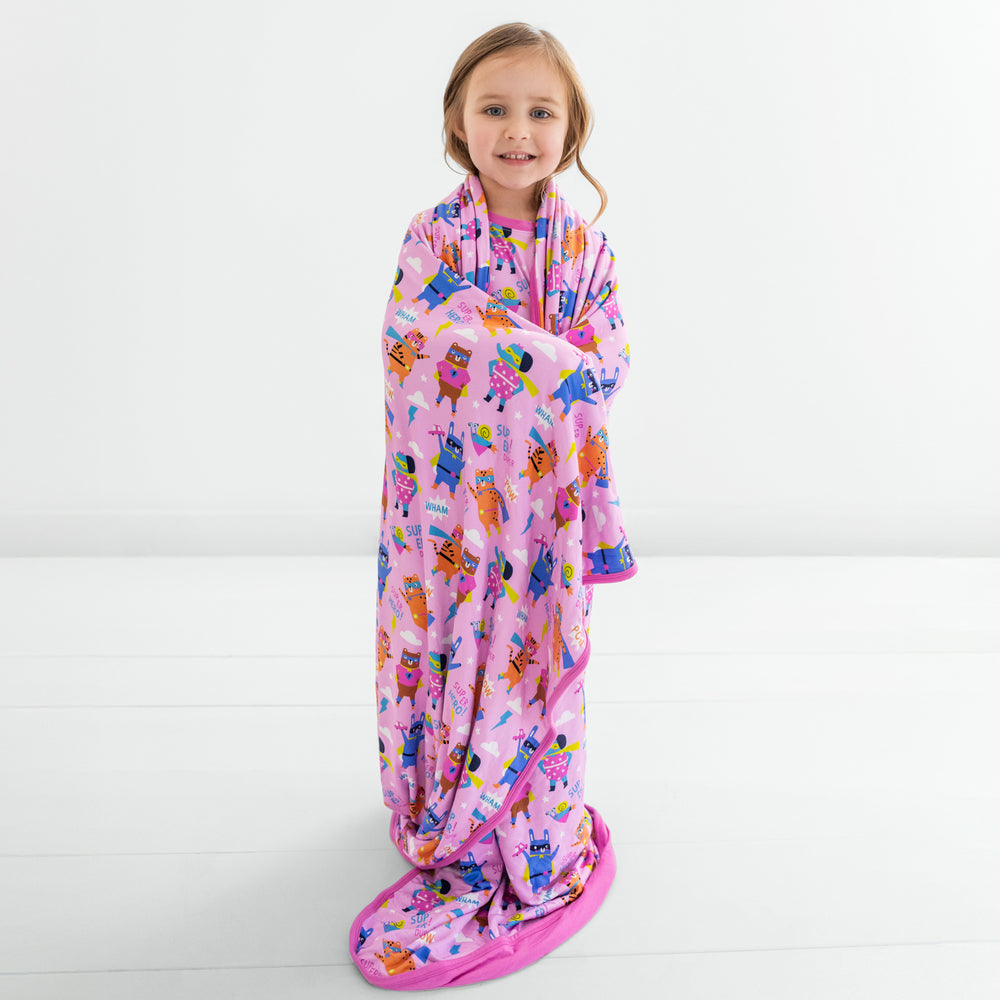 Child standing wrapped in a pink Sleepy Heroes Cloud Blanket