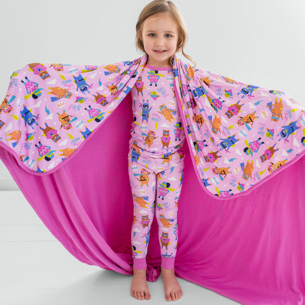 Child holding up the Pink Sleepy Heroes Cloud Blanket revealing the solid pink side