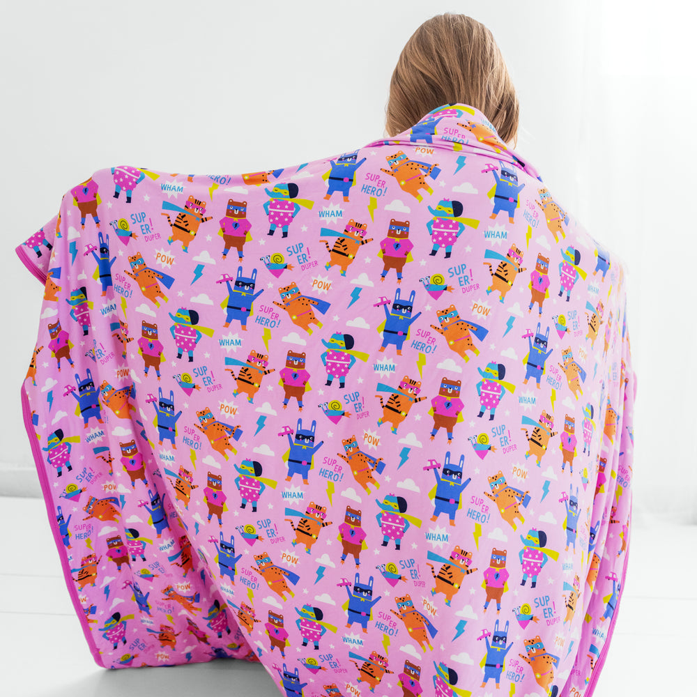 Child holding up the Pink Sleepuy Heroes Cloud Blanket showing the print