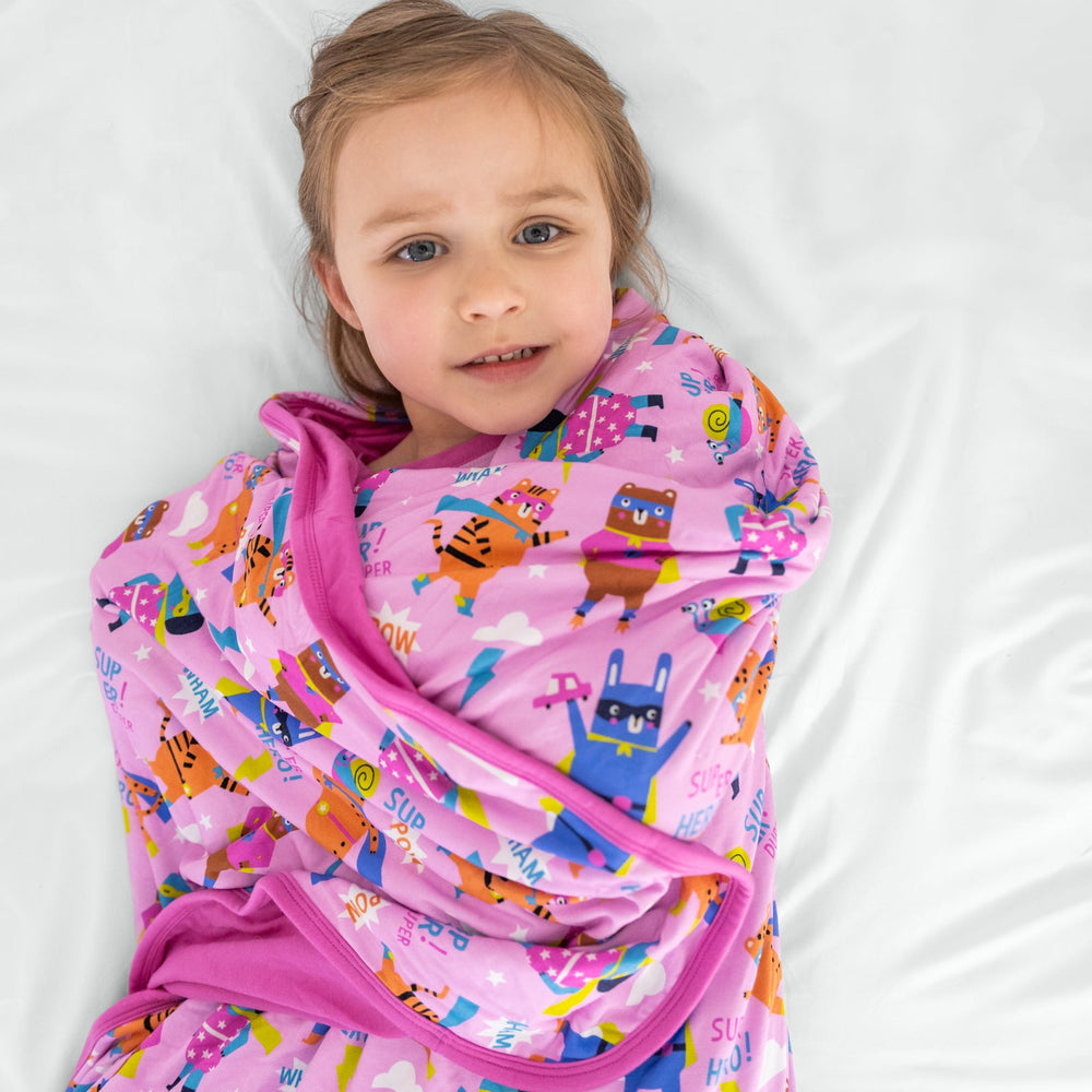 Child laying wrapped in the pink Sleepy Heroes Cloud Blanket