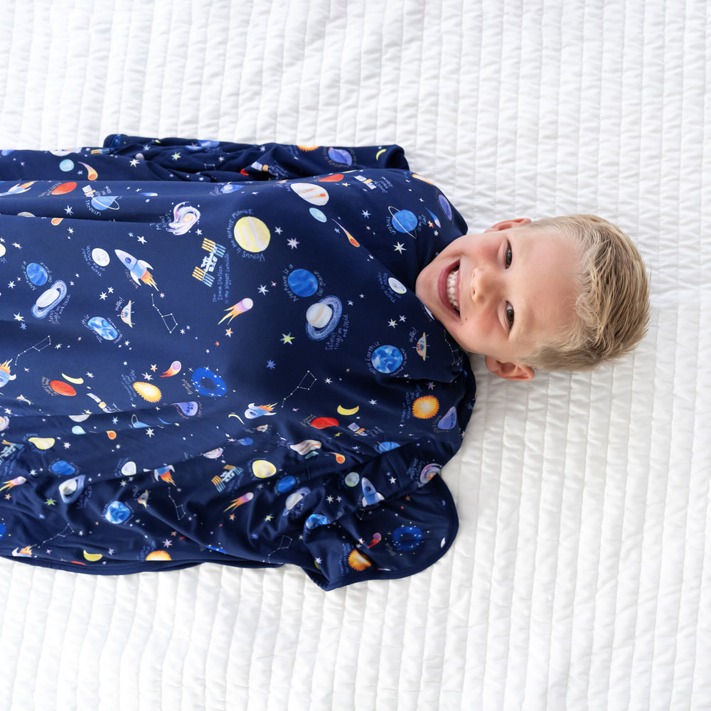 Close up image of a child wrapped in a Through My Telescope cloud blanket