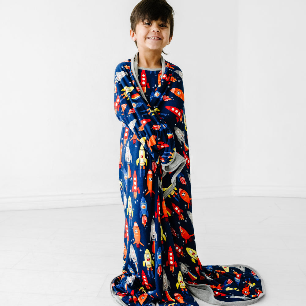 Child wrapped in a Navy space explorer cloud blanket