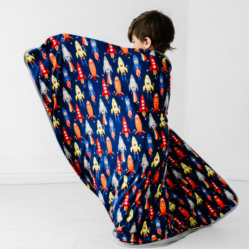 back view of a child holding up a Navy Space Explorer cloud blanket