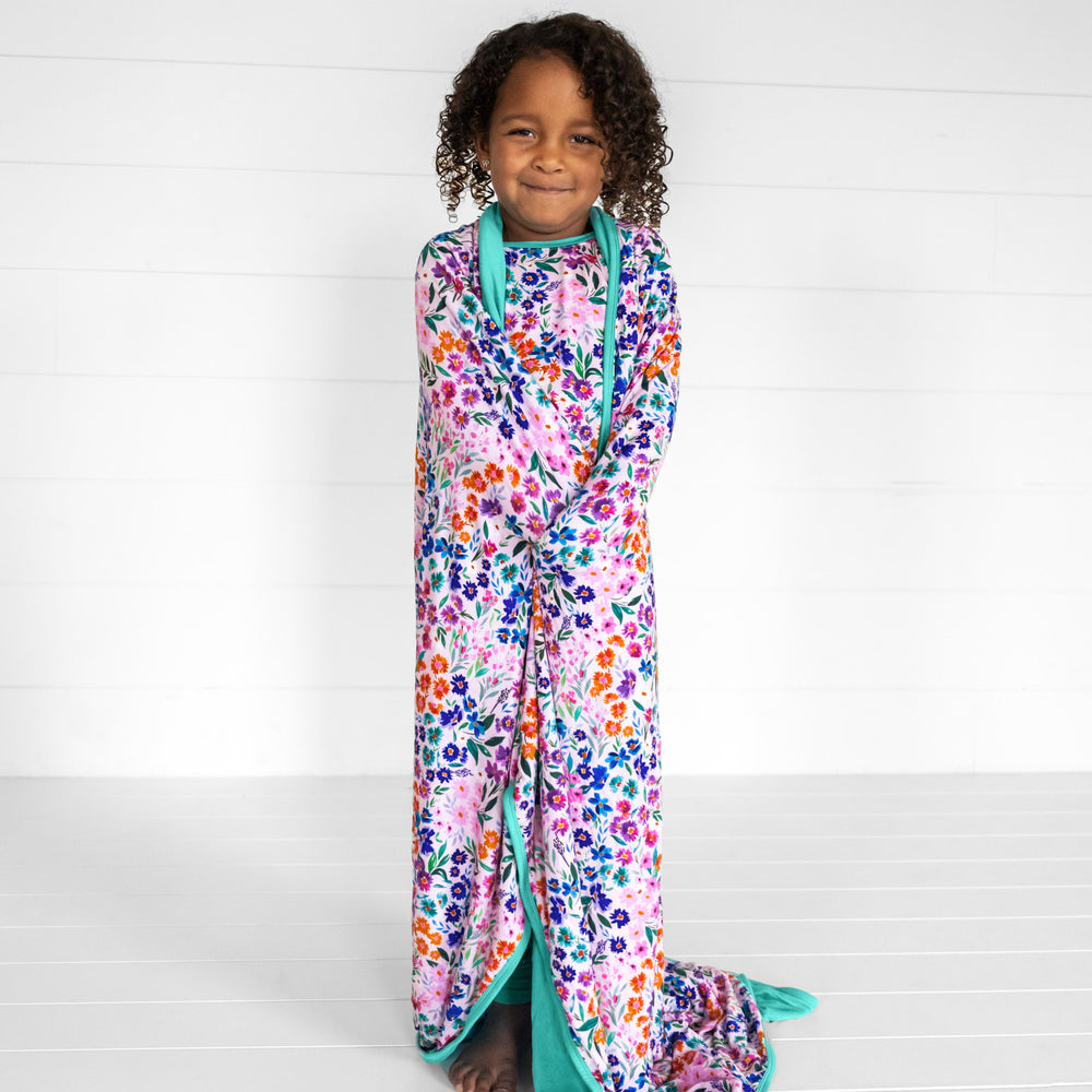 Image of a child wrapped in a Sweet Pea floral cloud blanket