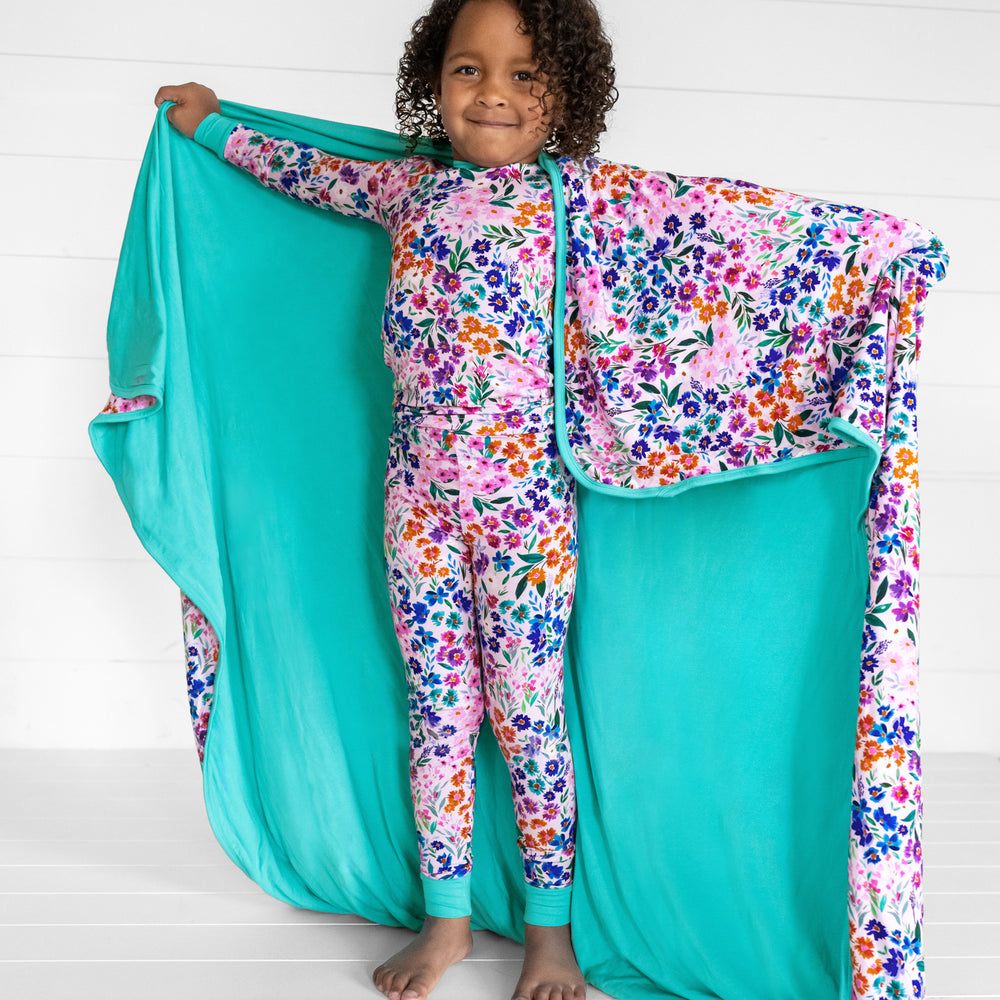 Image of a child wearing a Sweet Pea Floral two piece pj set holding out a Sweet Pea Floral cloud blanket