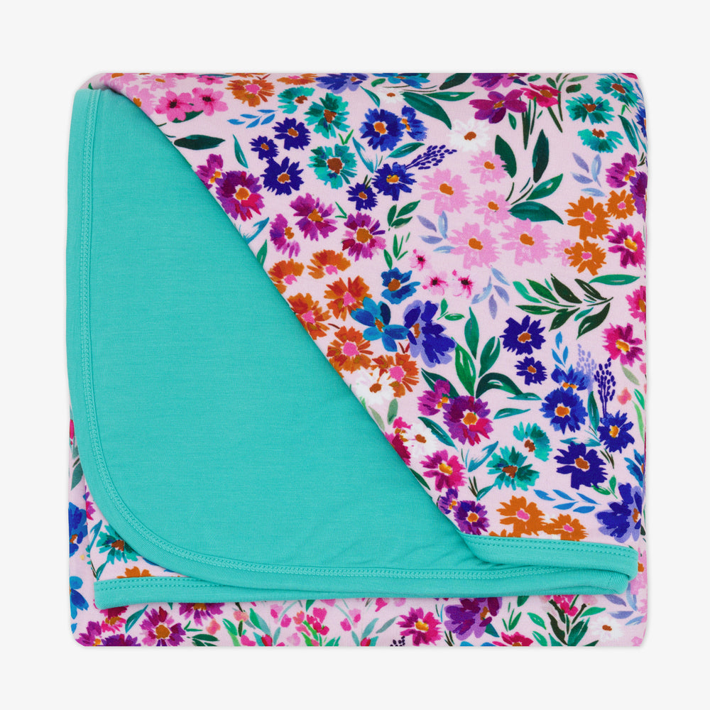 Flat lay image of a Sweet Pea Floral Cloud blanket showing the blue backing