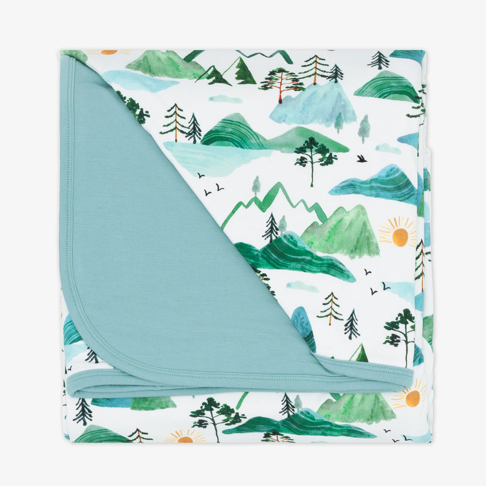 flat lay image of a mountain mist printed cloud blanket showing the solid blue backing