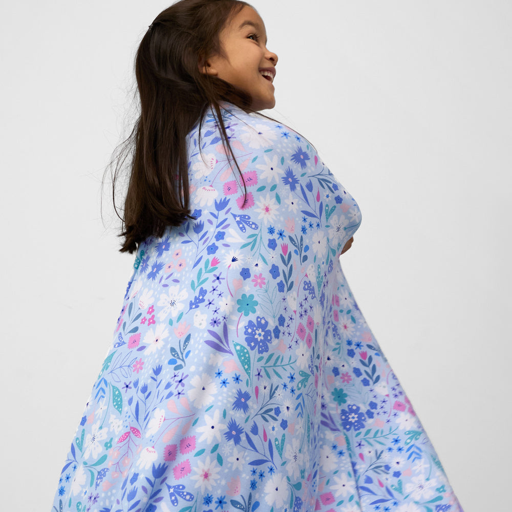 back image of a child wearing a Magical Meadow cloud blanket over her shoulders