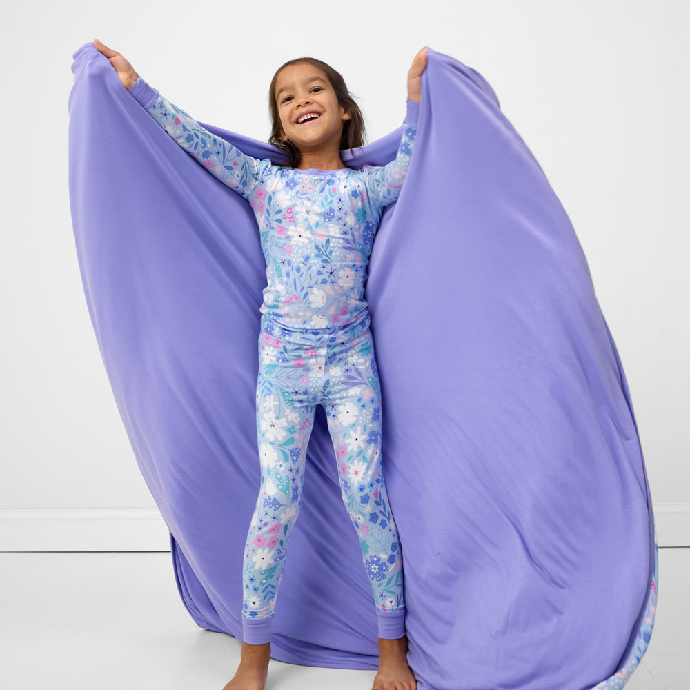 Image of a child holding out a Magical Meadow cloud blanket