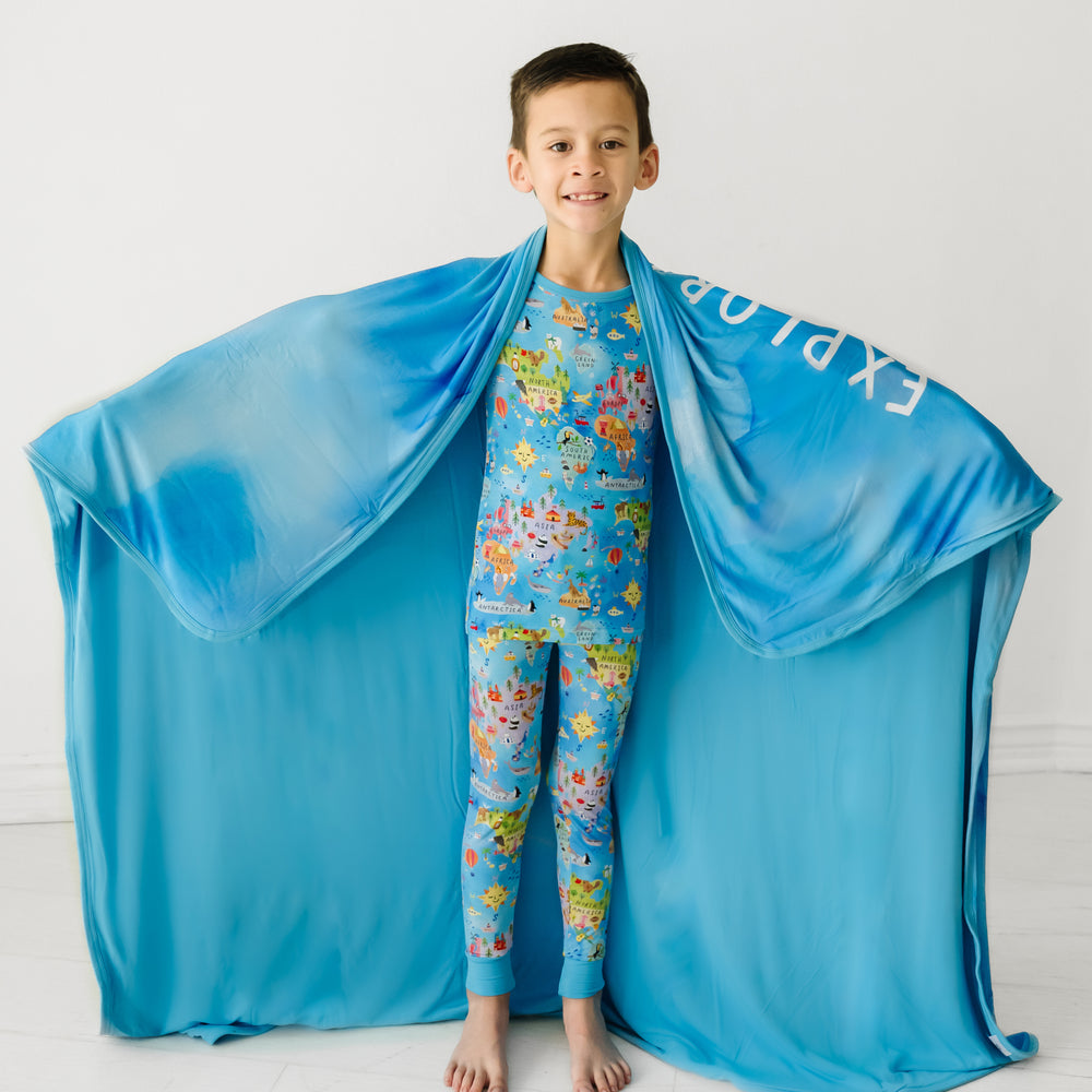 Child wearing an Around the World two piece pajama set with a matching cloud blanket draped over their shoulders