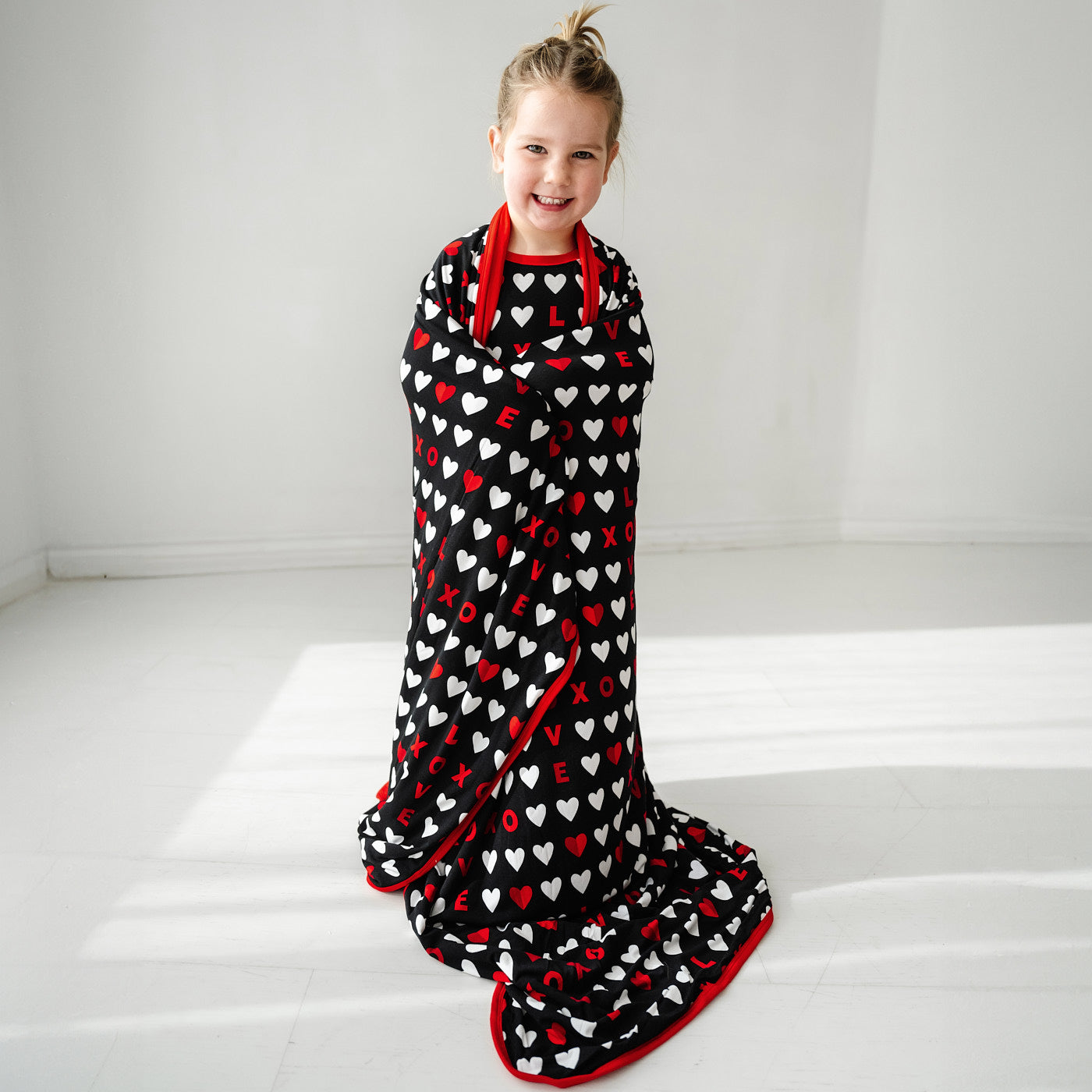 Child wrapped up in a Black XOXO large cloud blanket