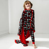 child wearing a Black XOXO two piece pajama set wearing a matching large cloud blanket over their shoulders
