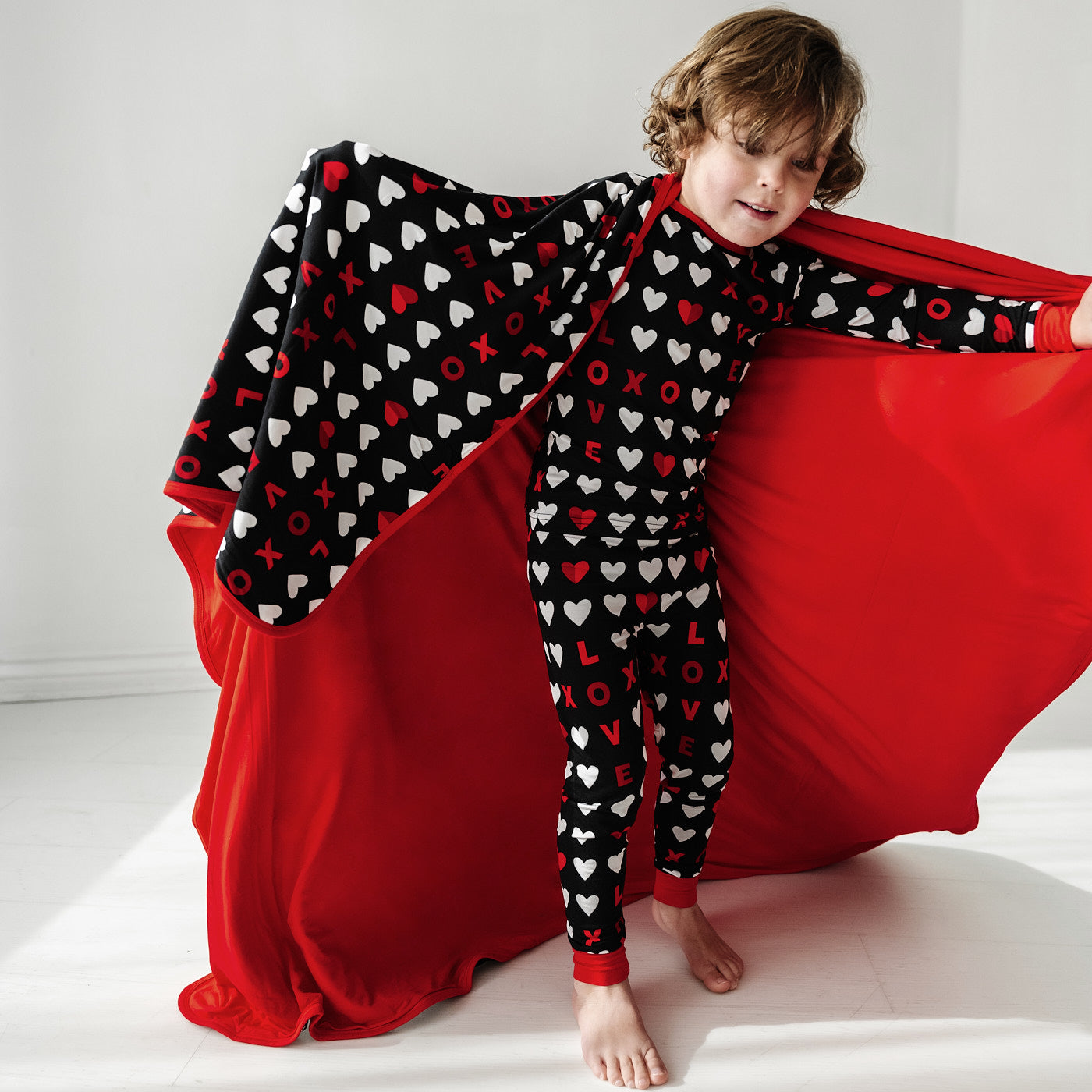 child running wearing a Black XOXO two piece pajama set holding up a matching large cloud blanket