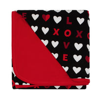 Flat lay image of a Black XOXO large cloud blanket showing the solid red backing