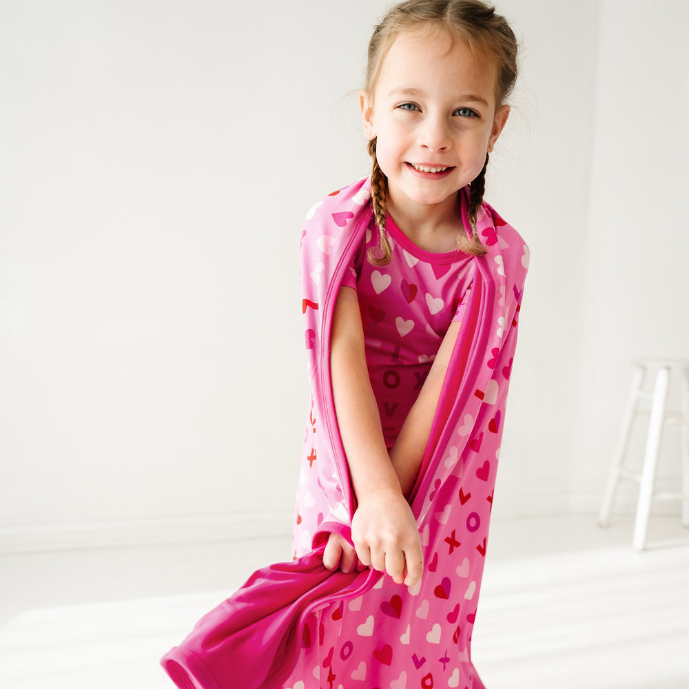 Click to see full screen - Close up image of a child wearing a Pink XOXO two piece pajama set wearing a matching large cloud blanket over their shoulders