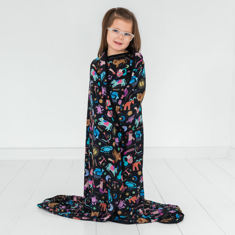 Image of a child wrapped in a Star Signs blanket and wearing a matching printed pj top