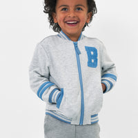 Close up image of a child wearing a Bluey gray bomber jacket with their hands in the pockets