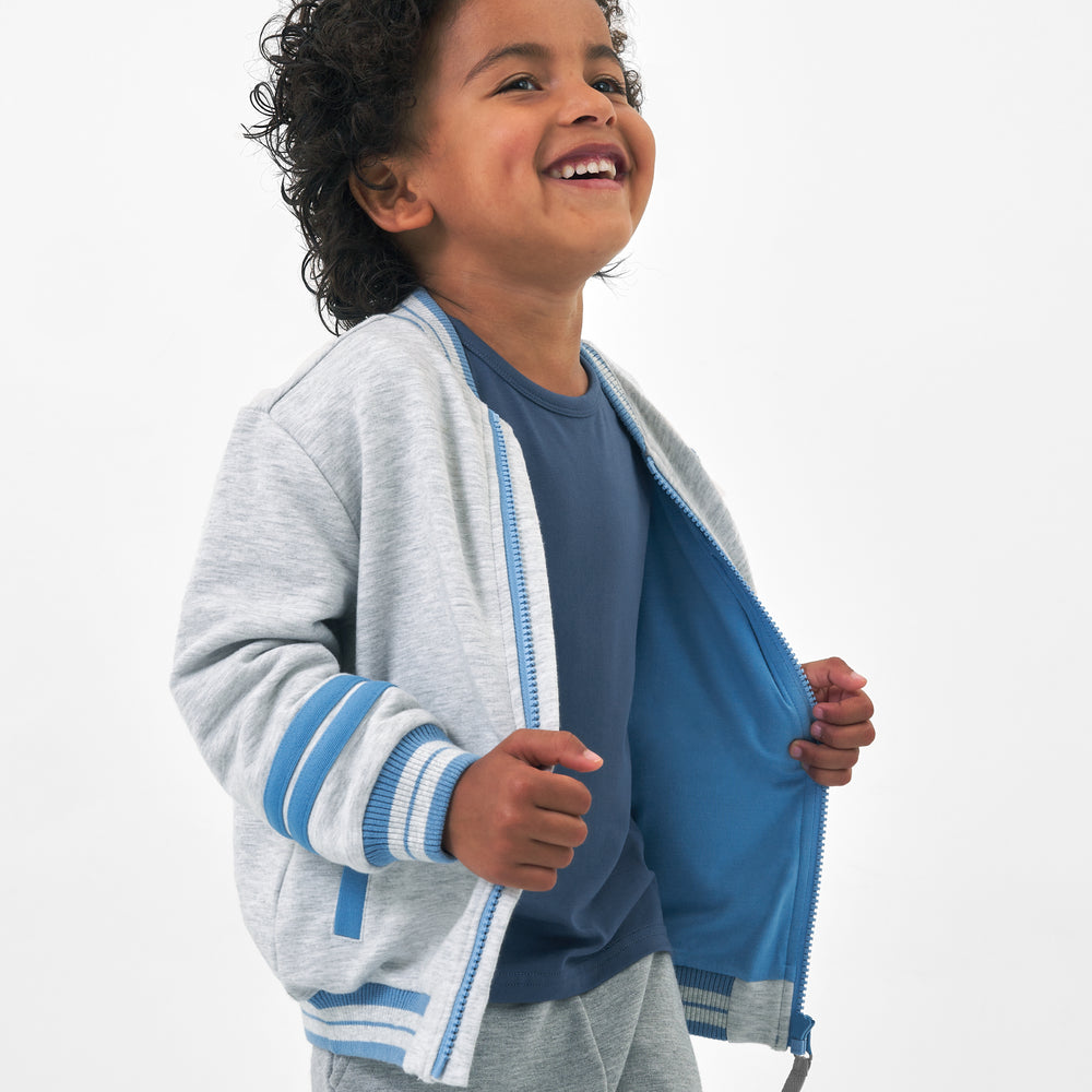Close up side view image of a child wearing a Bluey gray bomber jacket